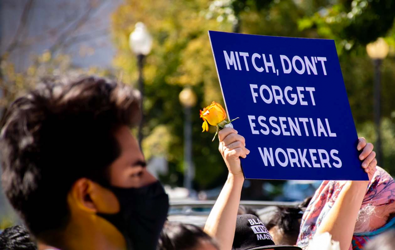 A photo of a man holding a sign in support of essential workers.