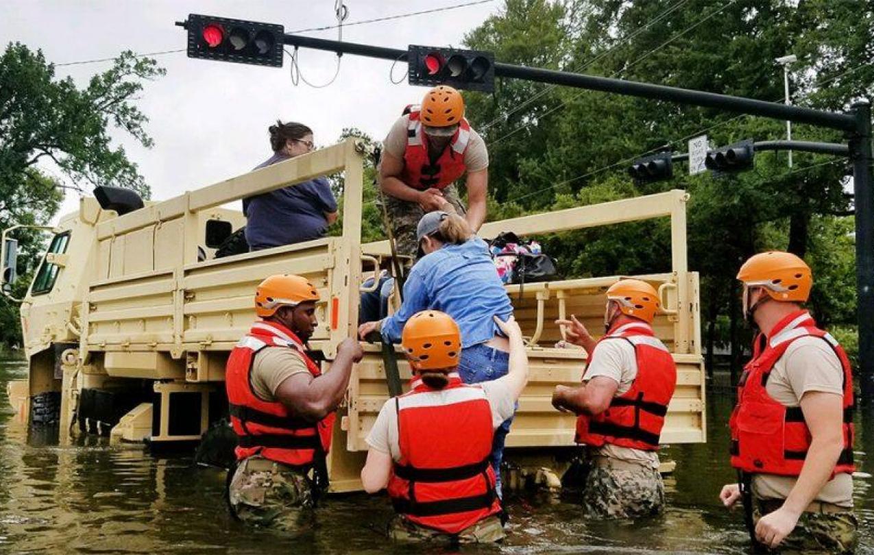 National Guard helping a woman into a truck during the Hurricane Harvey evacuation