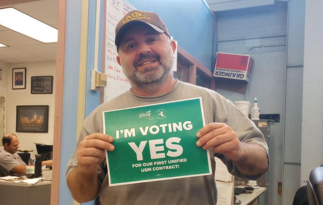 A photo of Cint Stevens holding an "I'm voting yes!" sign