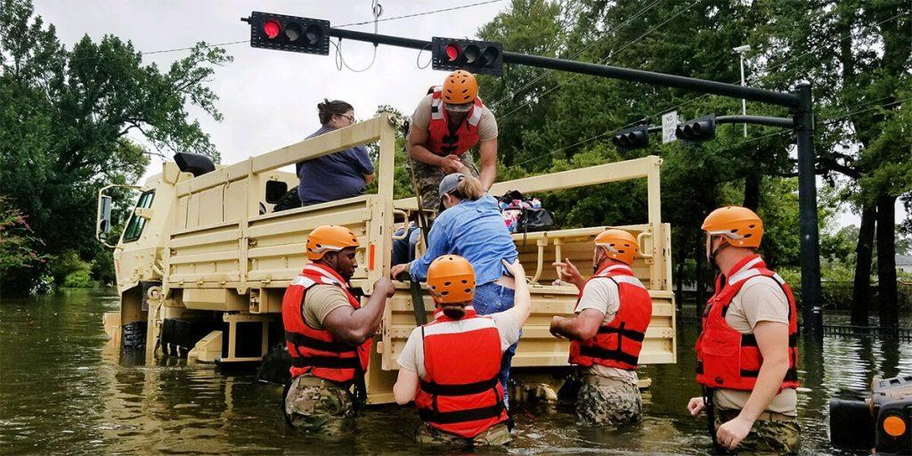 National Guard helping a woman into a truck during the Hurricane Harvey evacuation