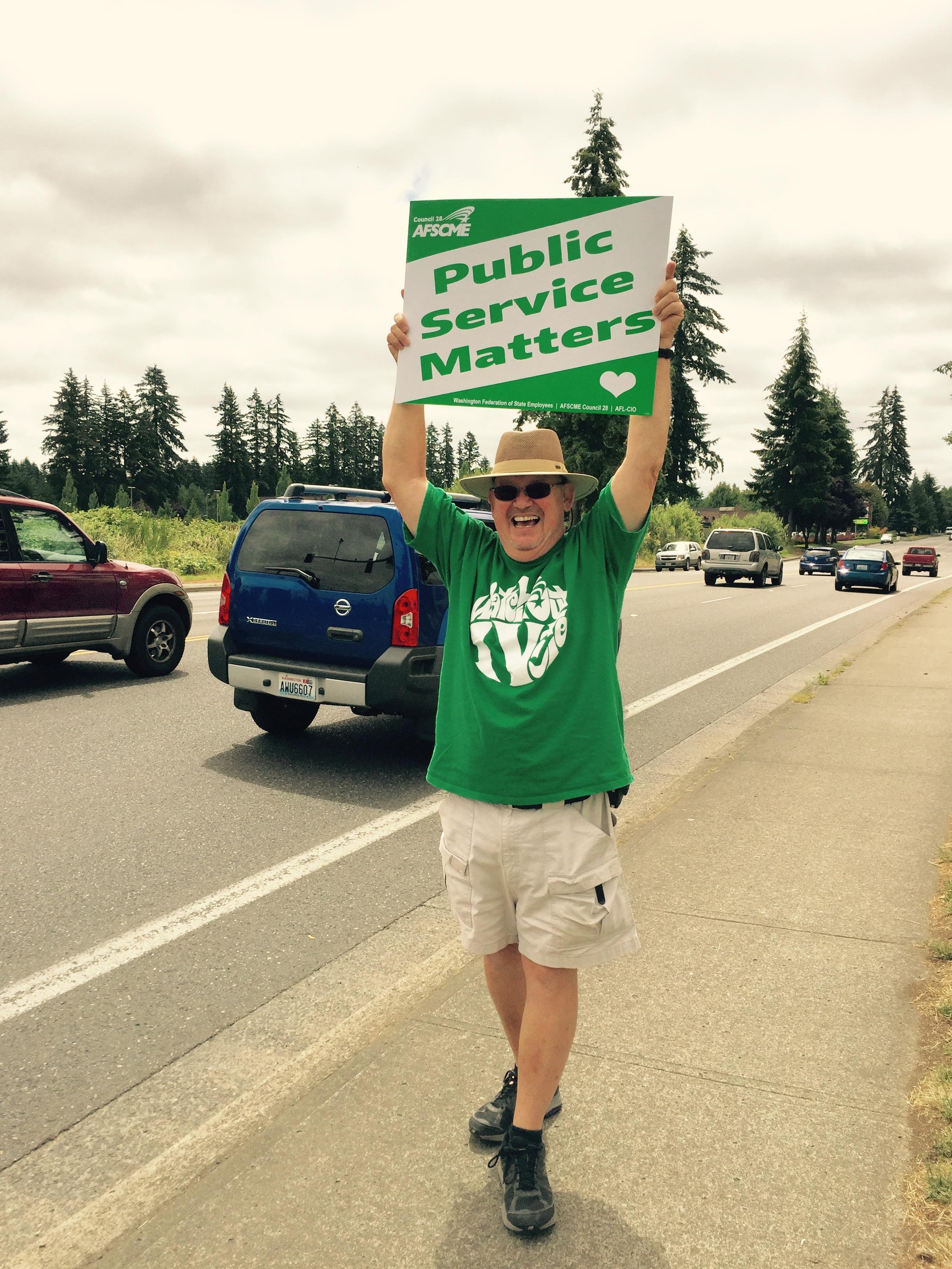 Tim Hughes holds up a sign saying "Public Service Matters"