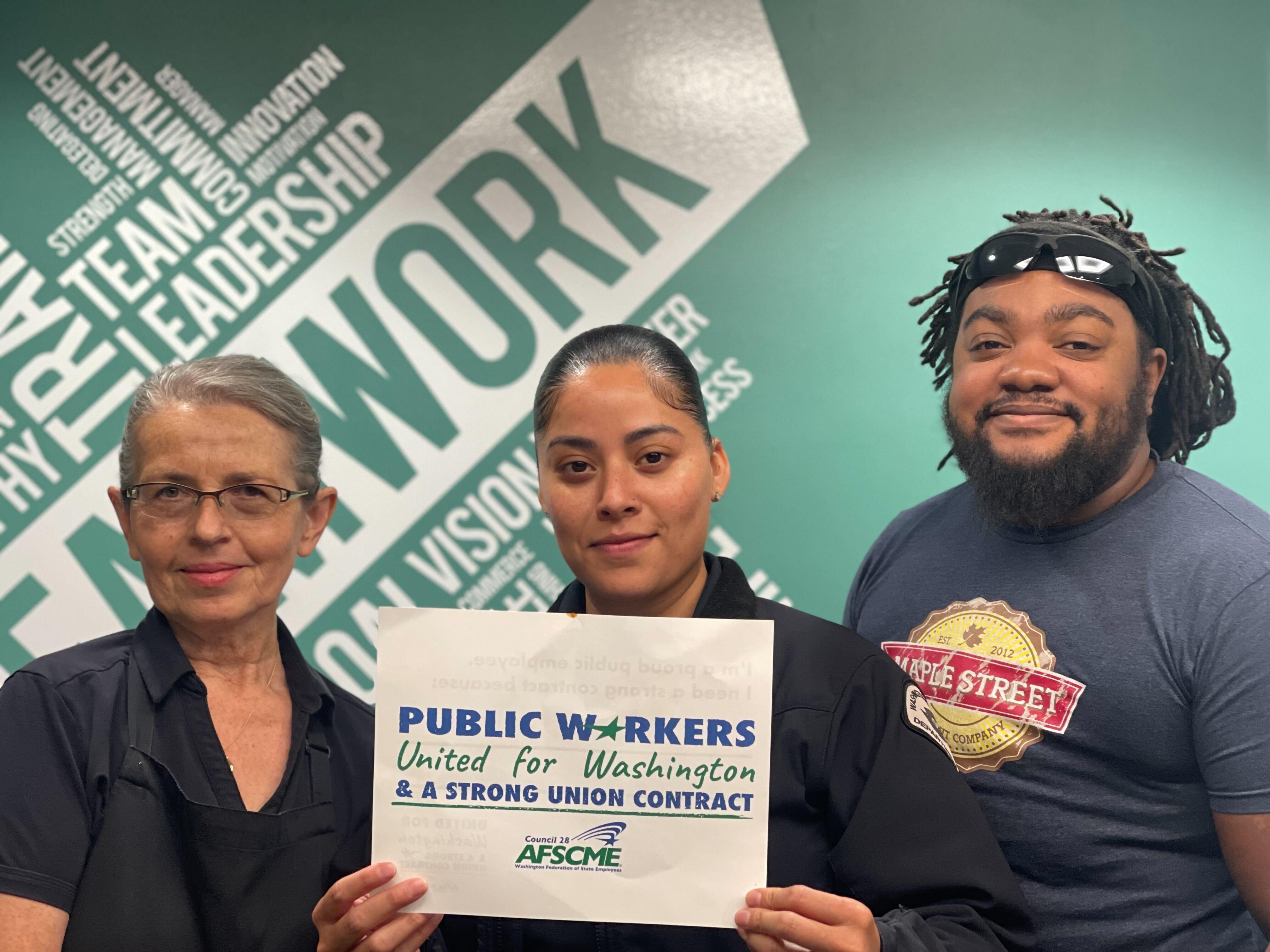 Three WFSE DOC members stand in front of a green background in green shirts with a white sign in WFSE branding that reads "United for Washington."
