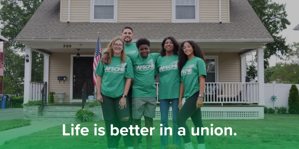 Group of AFSCME members in t-shirts with family members in front of a house with an American flag in the background.
